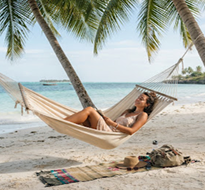 Relaxing on beach hammock under palm trees
